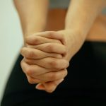 Back view of crop unrecognizable fit female in sportswear stretching arms and shoulders with fingers locked behind back before yoga session